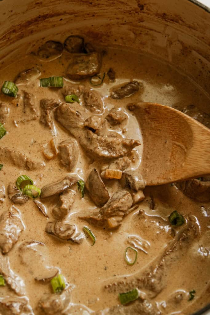 Beef stroganoff in a dutch oven with a wooden spoon.