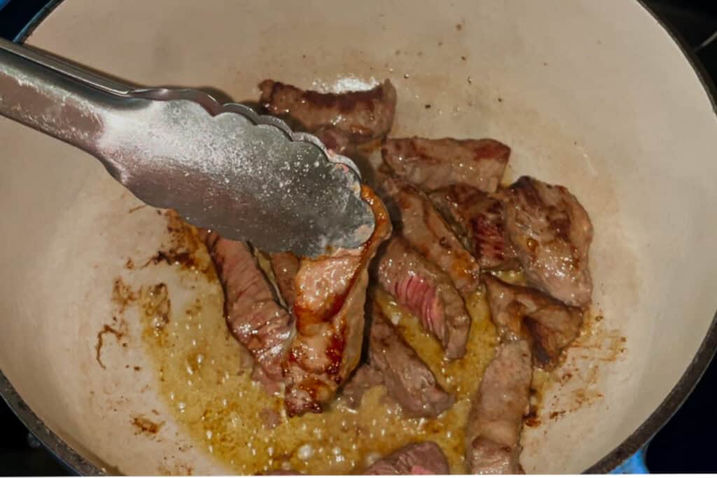 Browning steak pieces in a dutch oven.