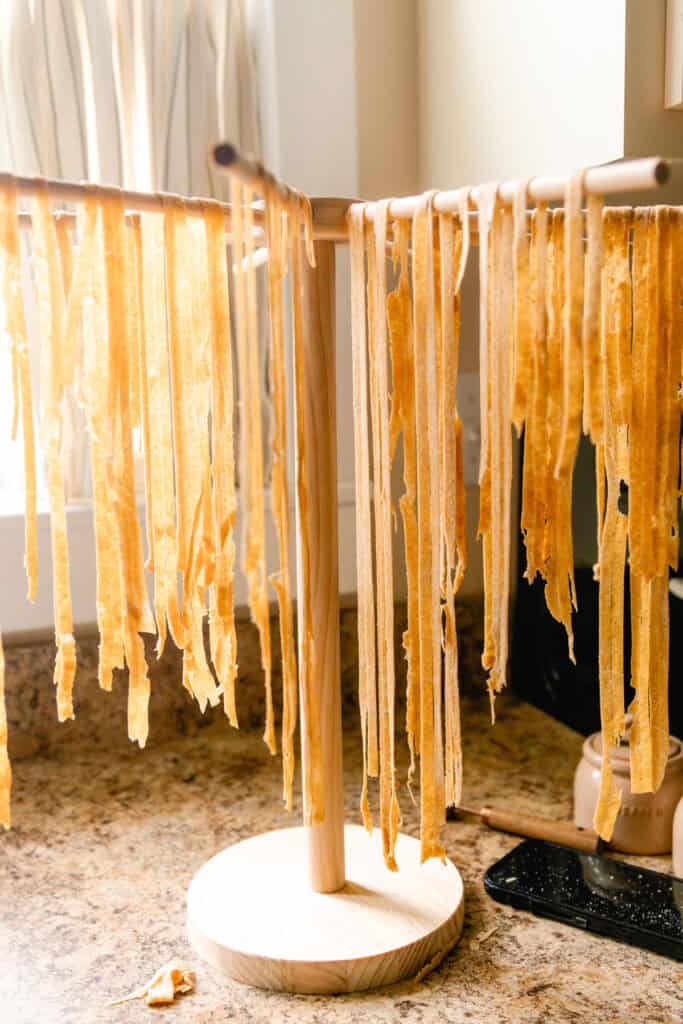 Whole wheat noodles hanging on a drying rack.