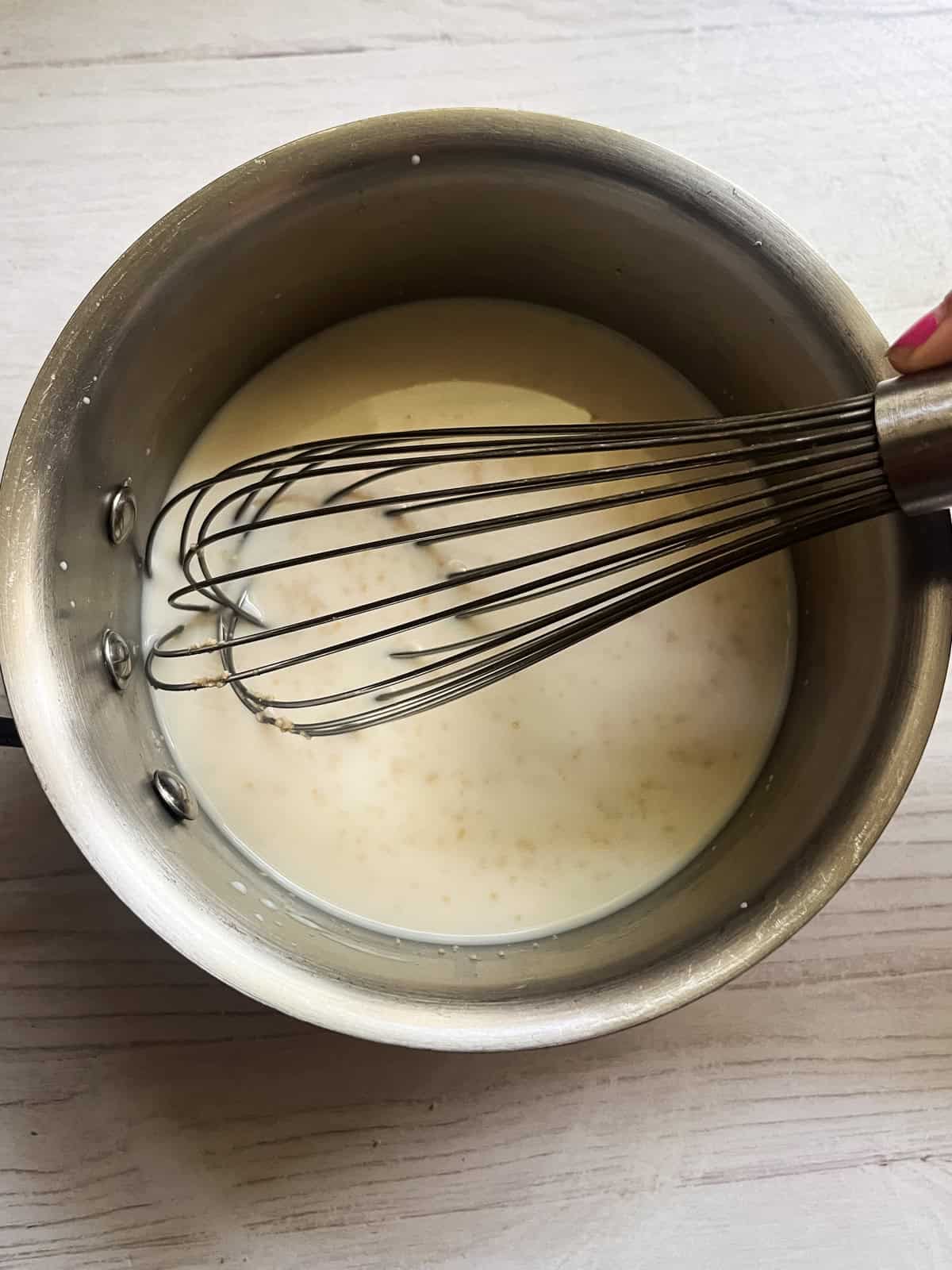 Stirring milk and yeast in a saucepan.