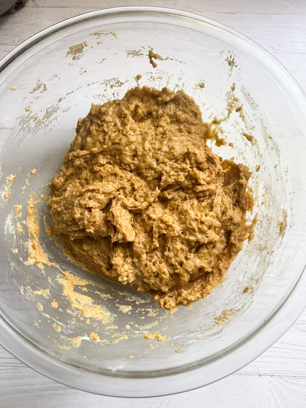 Hot dog bun dough just mixed in a glass mixing bowl.