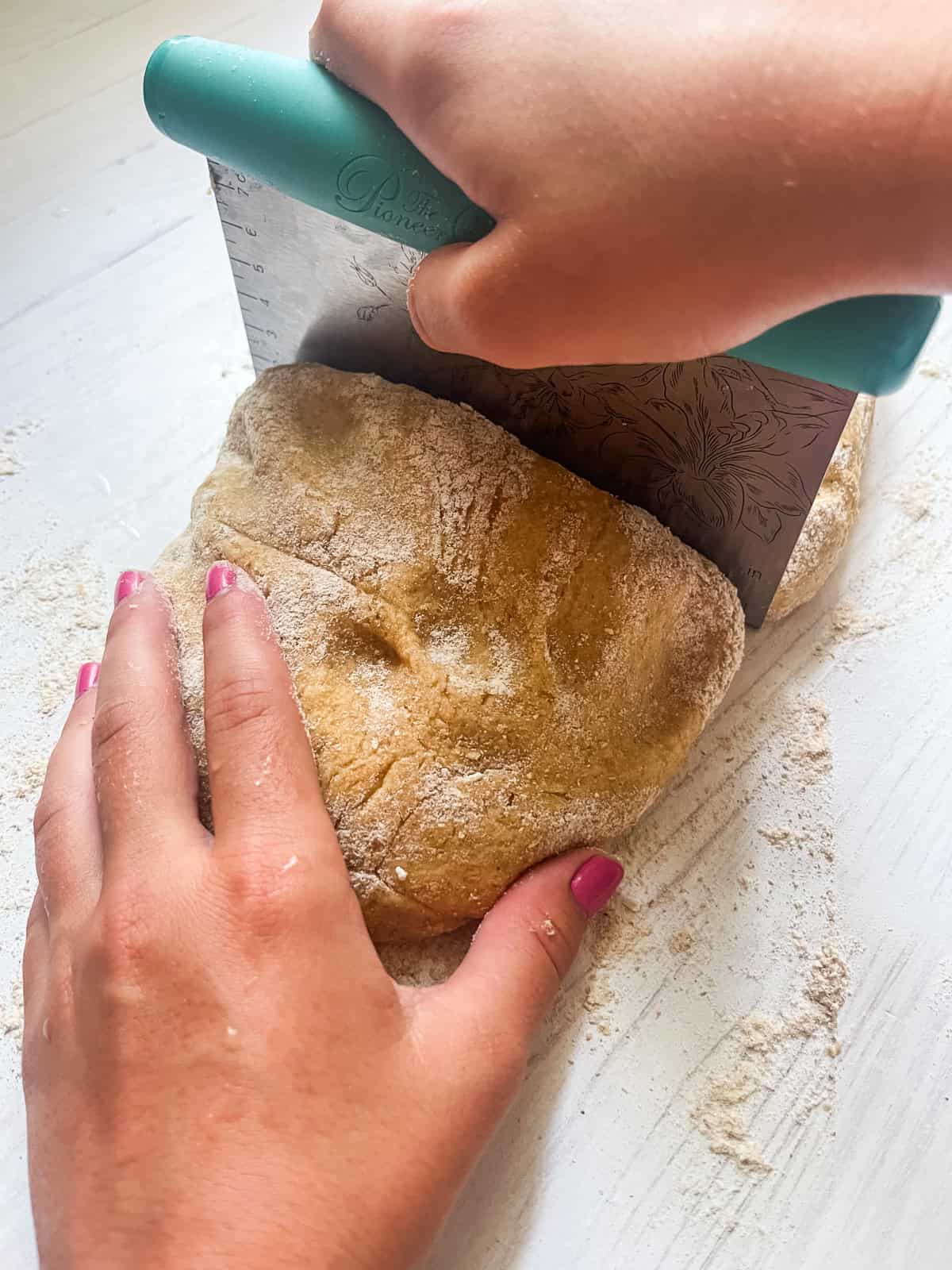 Using a pastry cutter to cut the dough into smaller pieces.