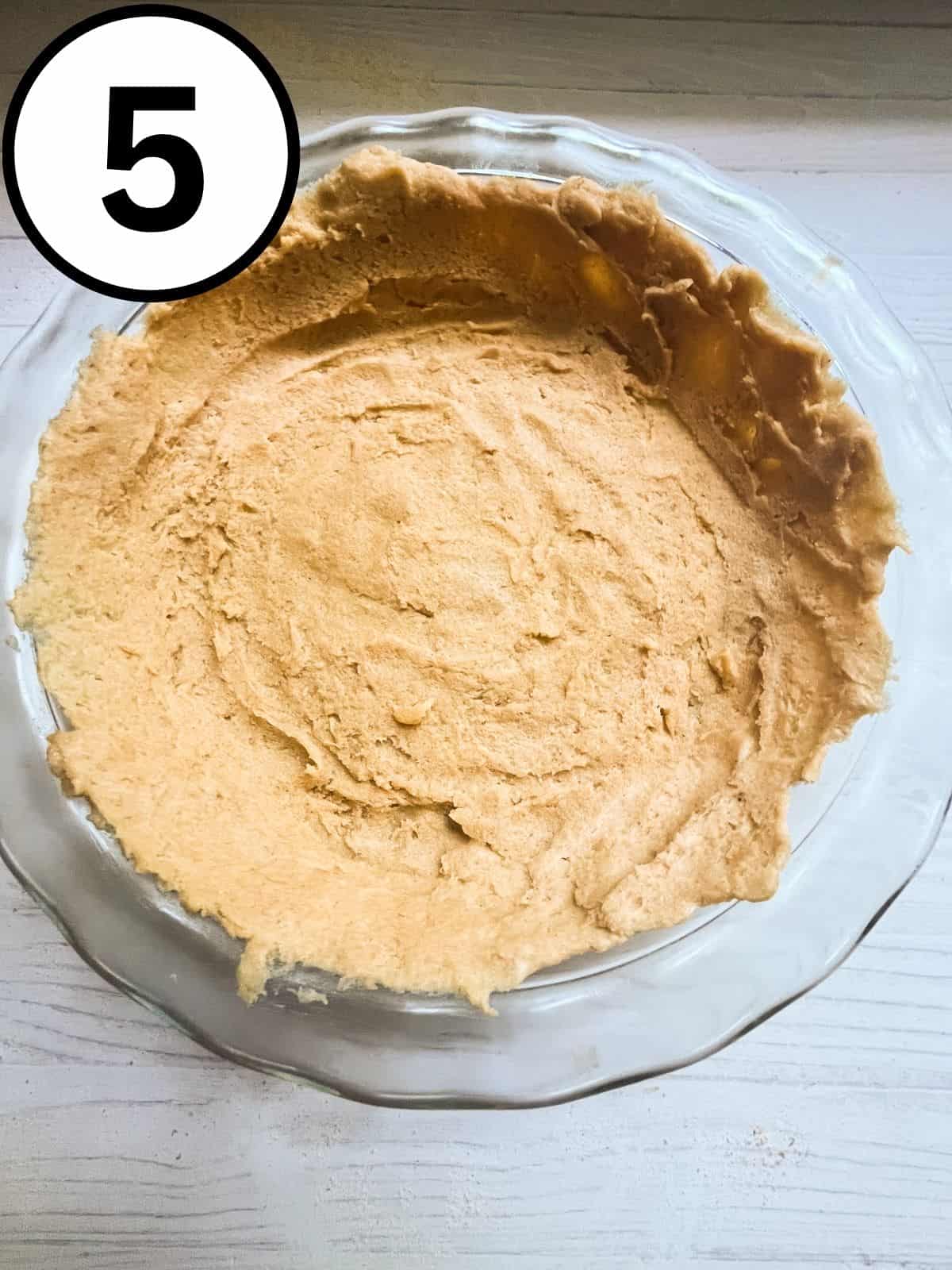 Raw pie crust laid out in a glass pie dish.