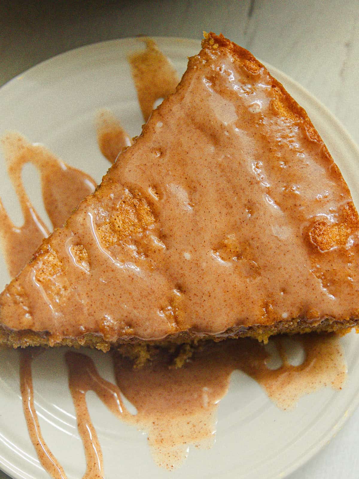 A slice of apple cider cake drizzled with glaze.