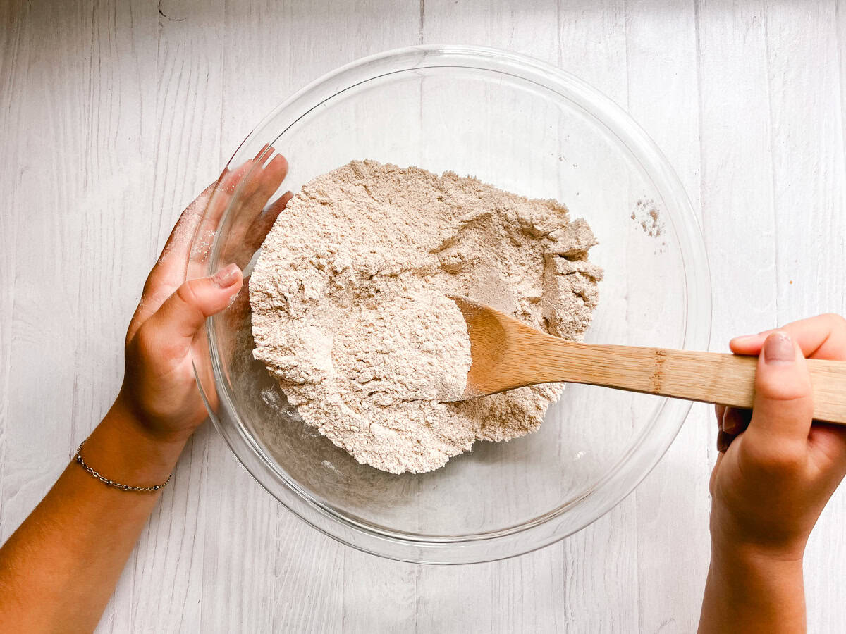 Stirring dry ingredients in a glass bowl with a wooden spoon. 