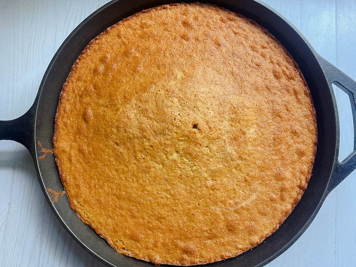 Apple cider cake in a cast iron skillet after baking to golden brown.