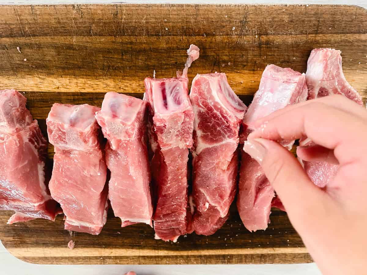 Sprinkling salt and pepper onto country-style ribs.