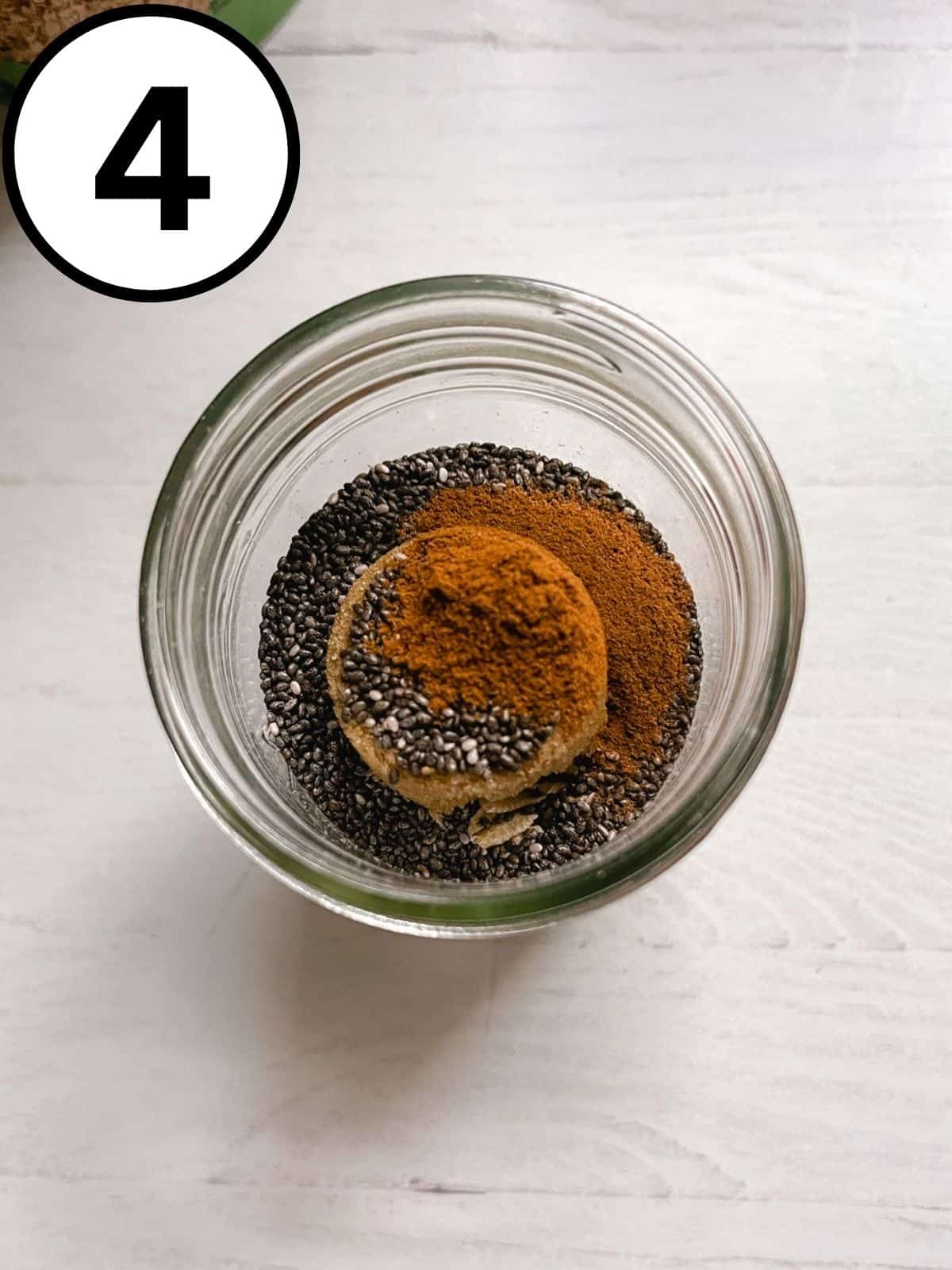Cinnamon added to a jar with chia seeds, brown sugar, and oats.