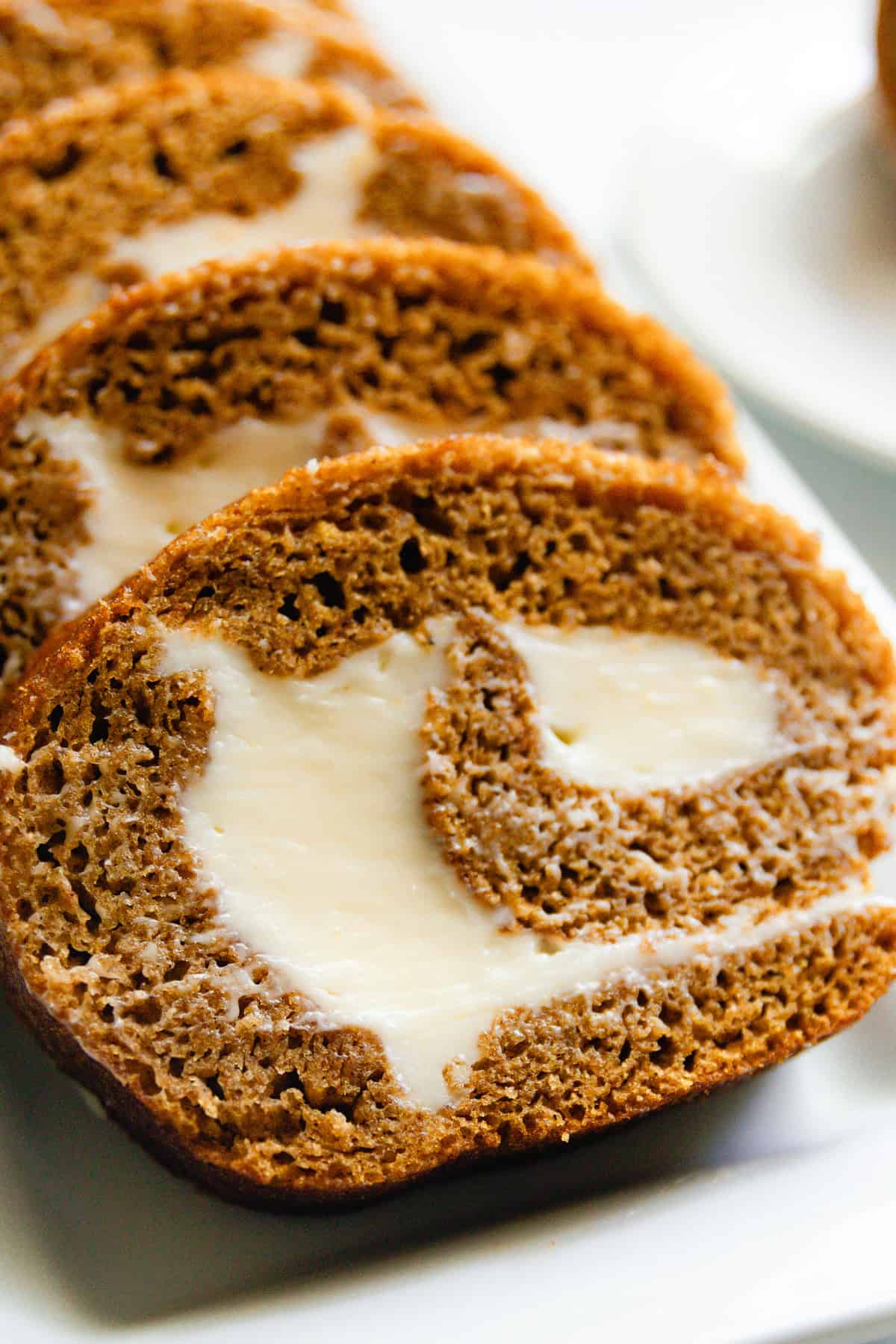 A whole grain pumpkin roll sliced on a white plate.