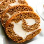 A whole grain pumpkin roll sliced on a white plate.