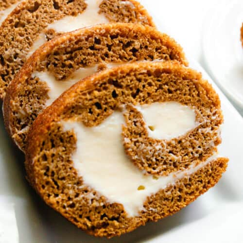 A whole grain pumpkin roll sliced on a white plate.