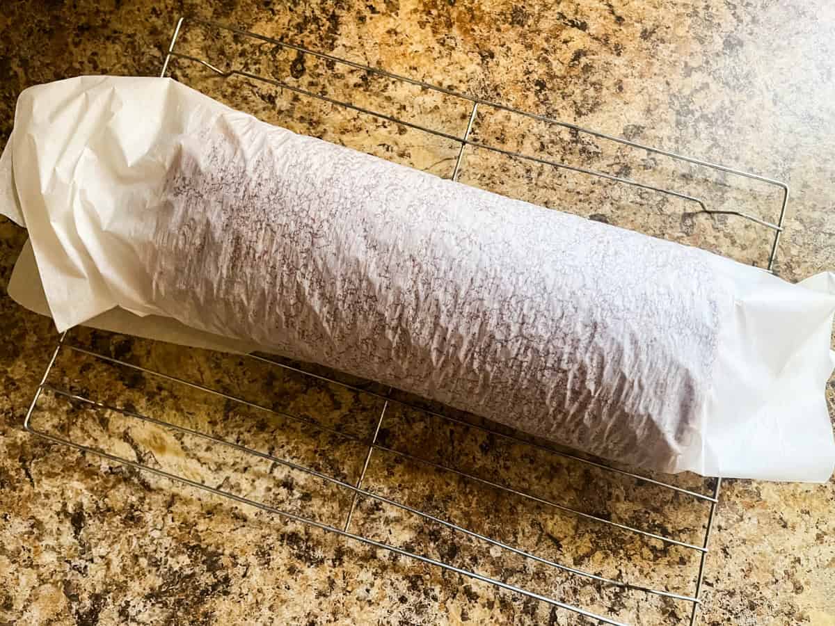 Pumpkin bread rolled into a spiral in a sheet of parchment paper.