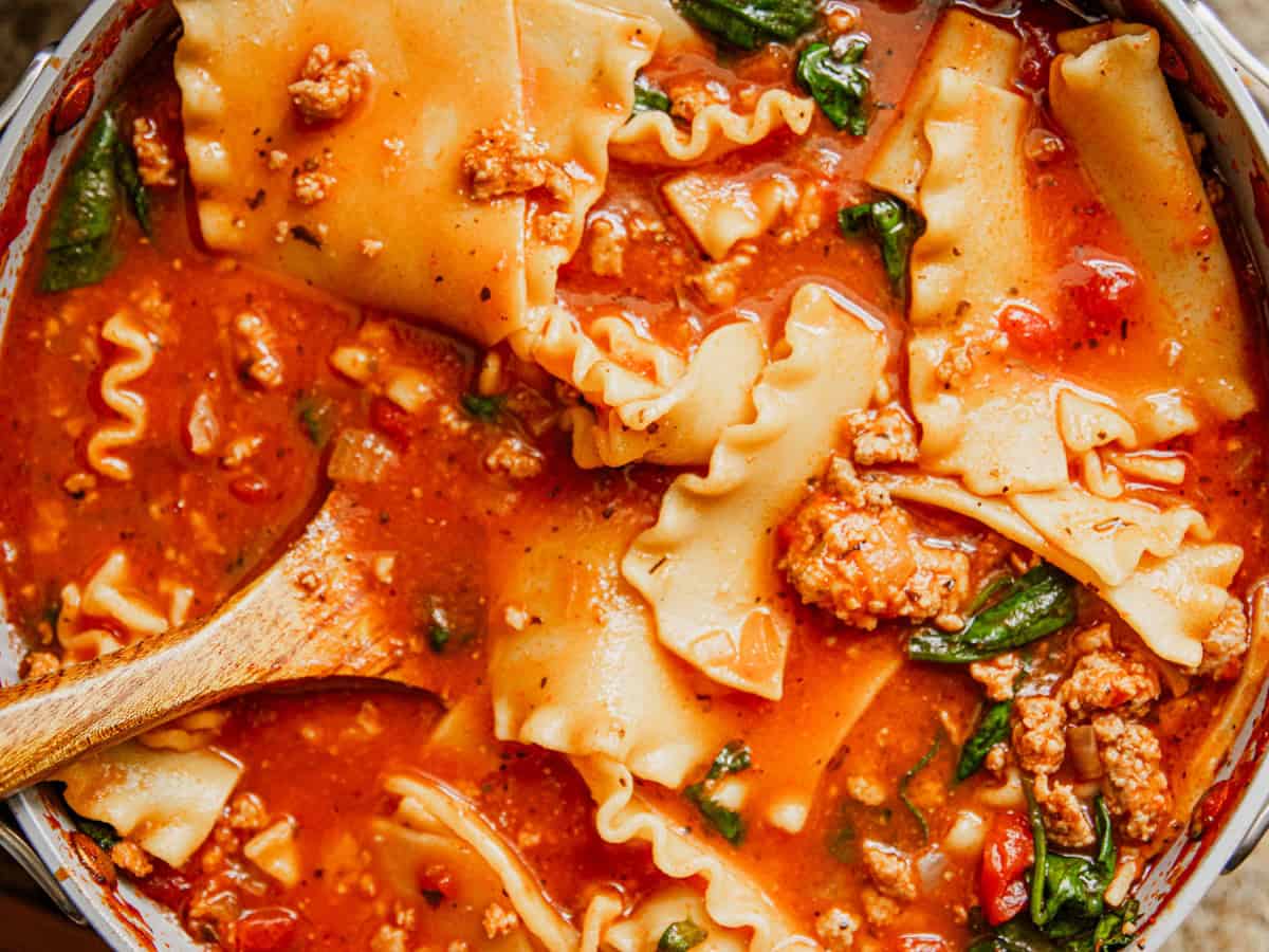 A close-up of lasagna soup with a spoon in it. 