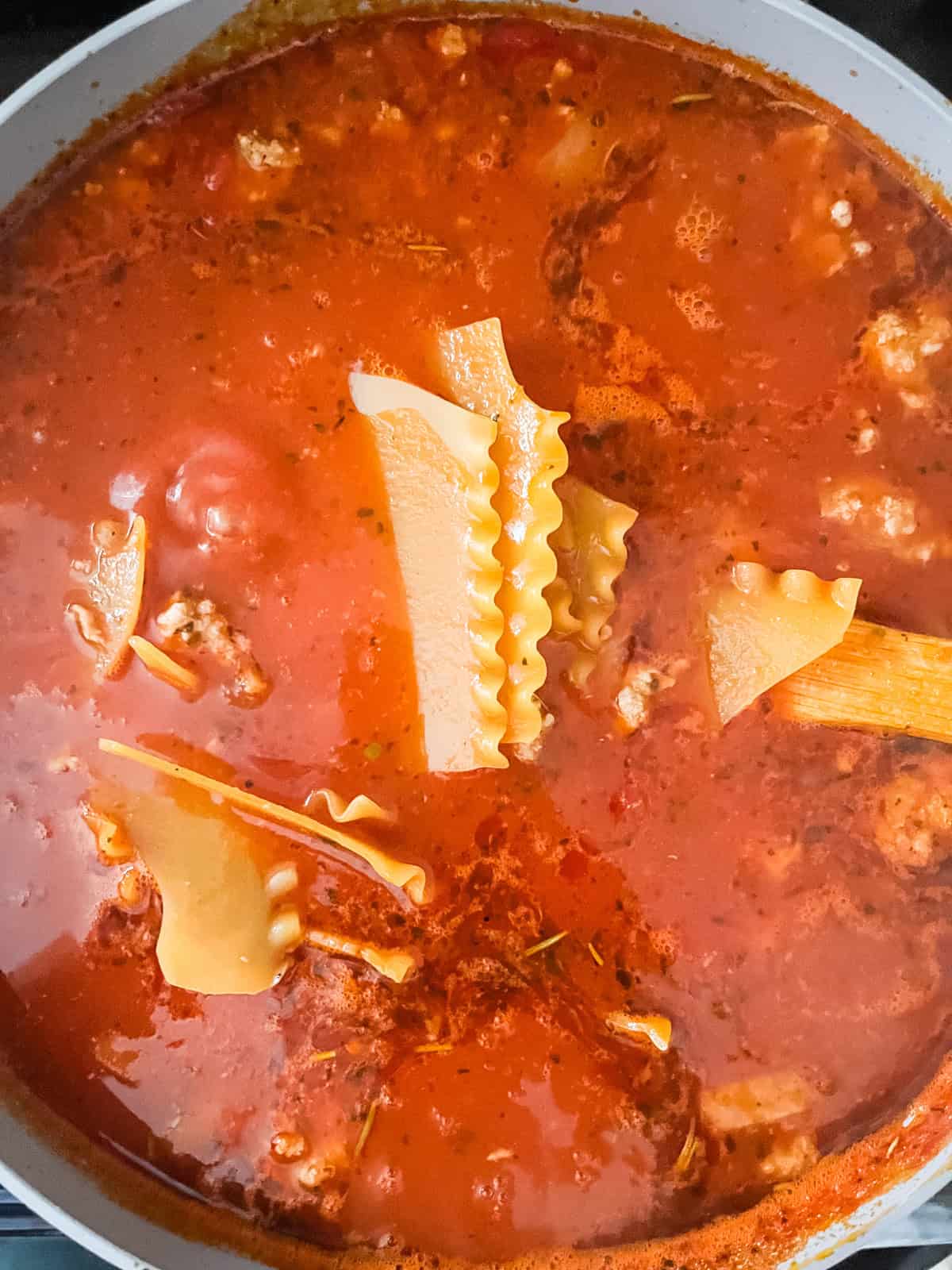 Lasagna noodles in a pot of soup before cooking. 