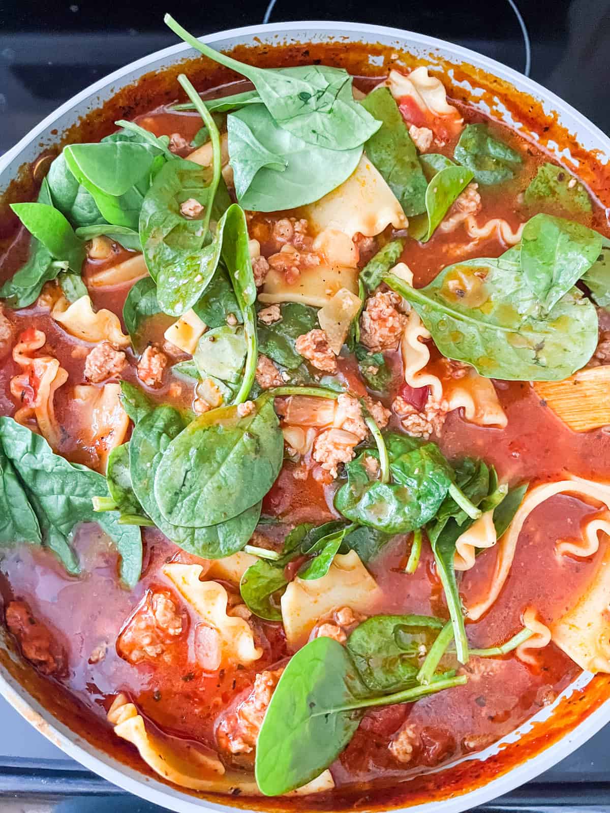 Spinach added to a pot of lasagna soup. 