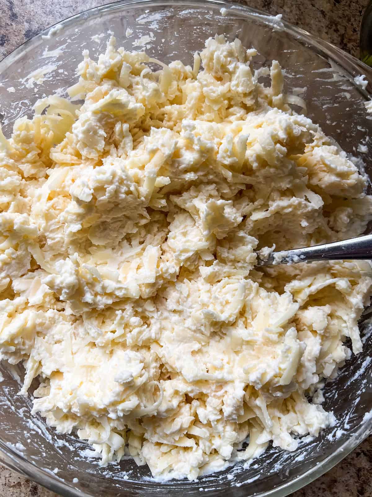 Ricotta cheese and shredded cheese mixed together in a small bowl. 