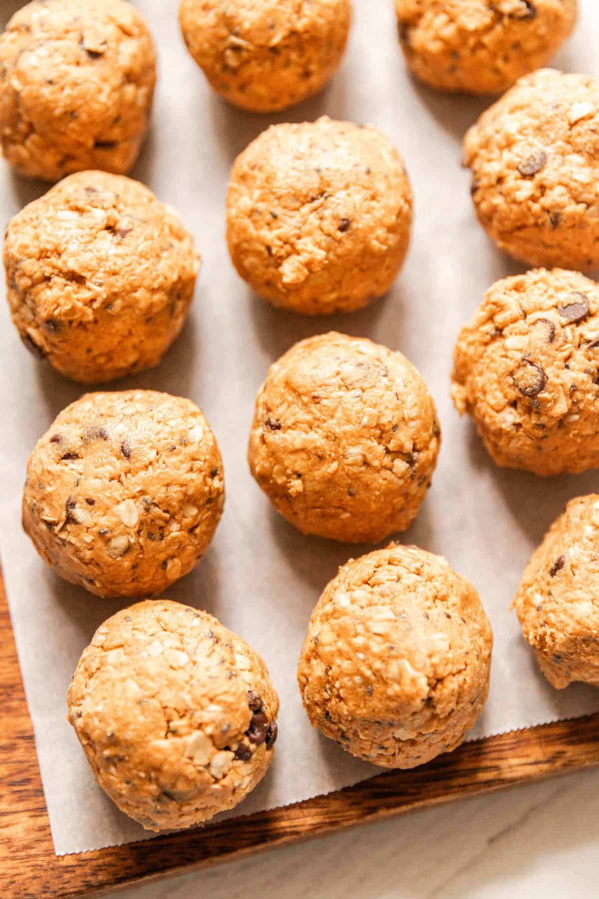 Protein balls lined up on a parchment paper-lined baking sheet.