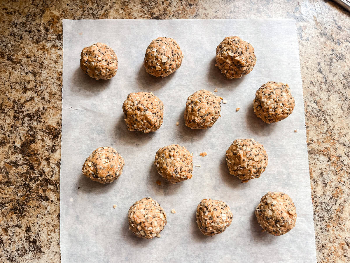 Protein balls lined up on a parchment paper-lined baking sheet. 