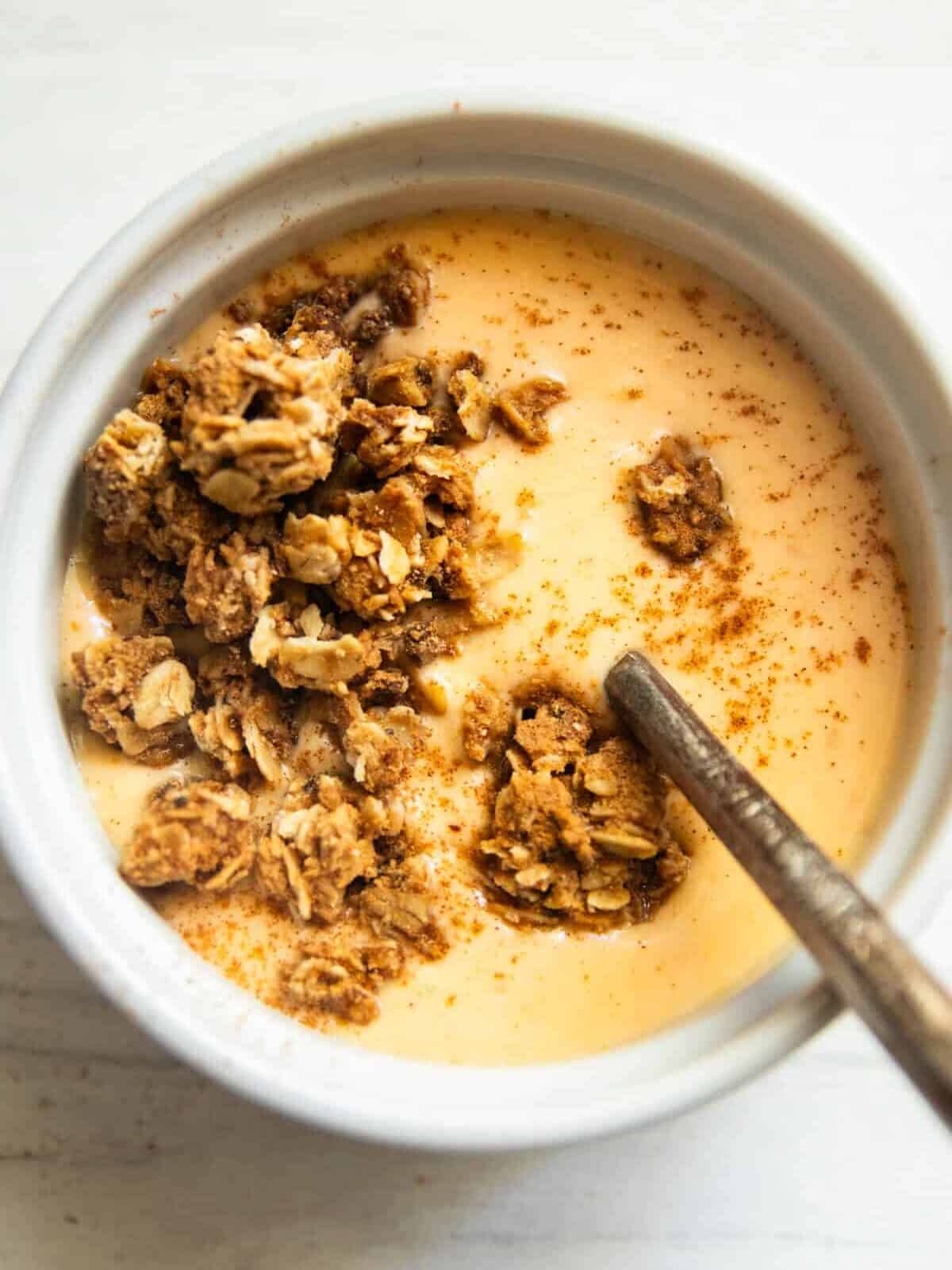 A bowl of pumpkin yogurt with granola on top. 