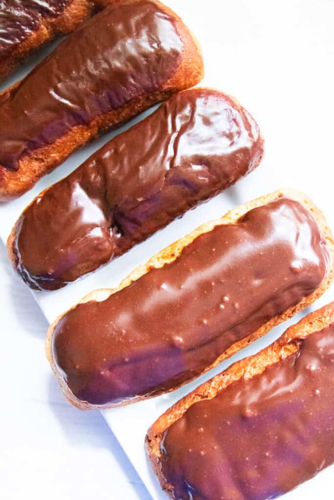 Whole grain long john donuts lined up on a white background.