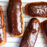 Whole grain long john donuts scattered on a cooling rack.