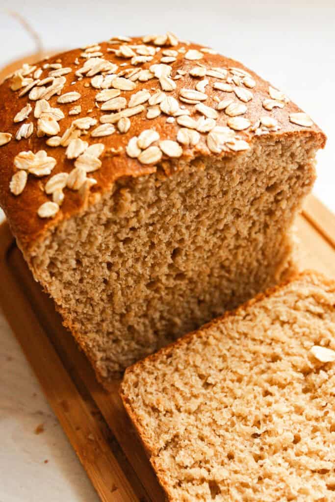 A loaf of whole grain seeded bread with a slice cut off.