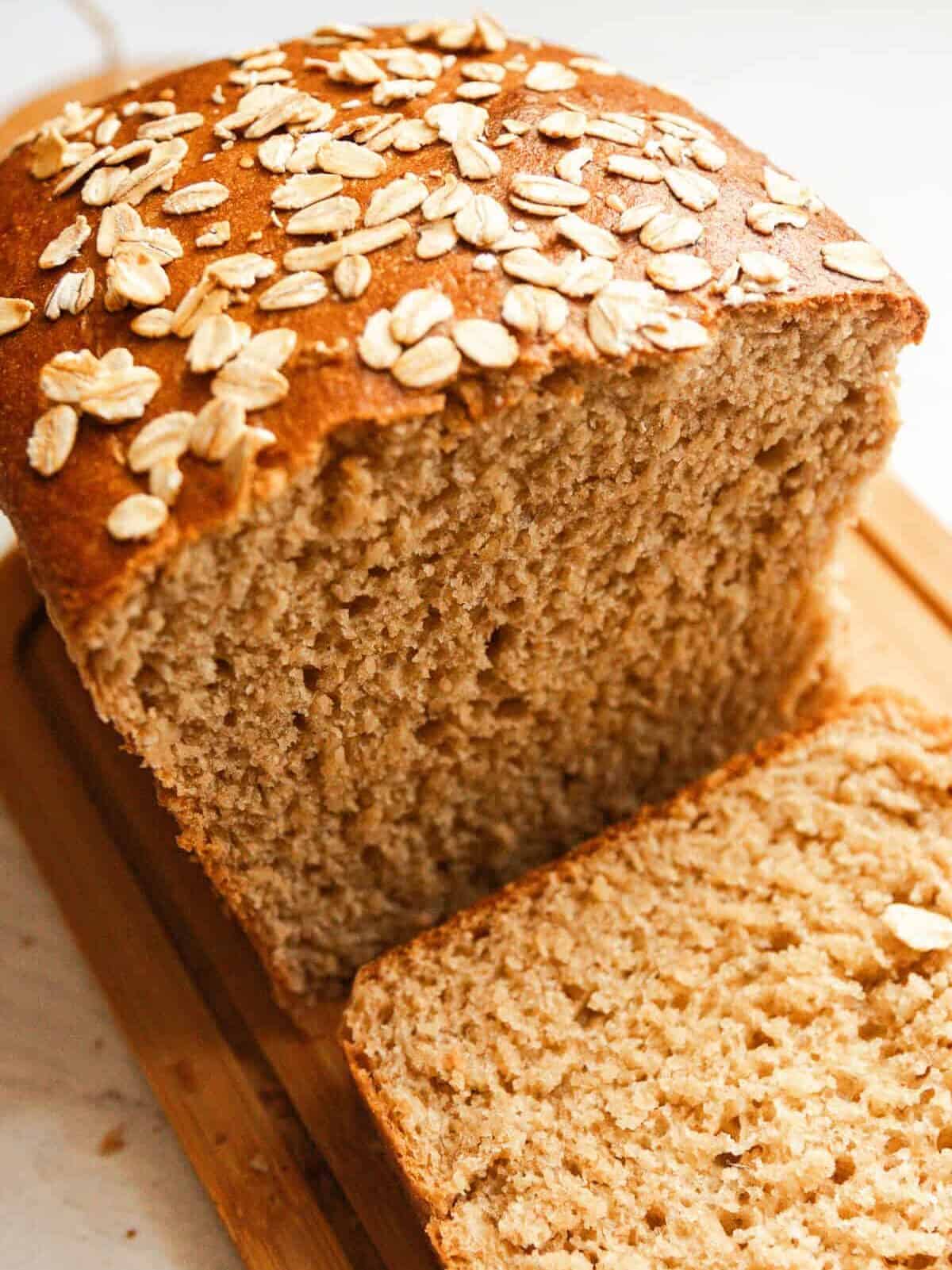 A loaf of whole grain seeded bread with a slice cut off.