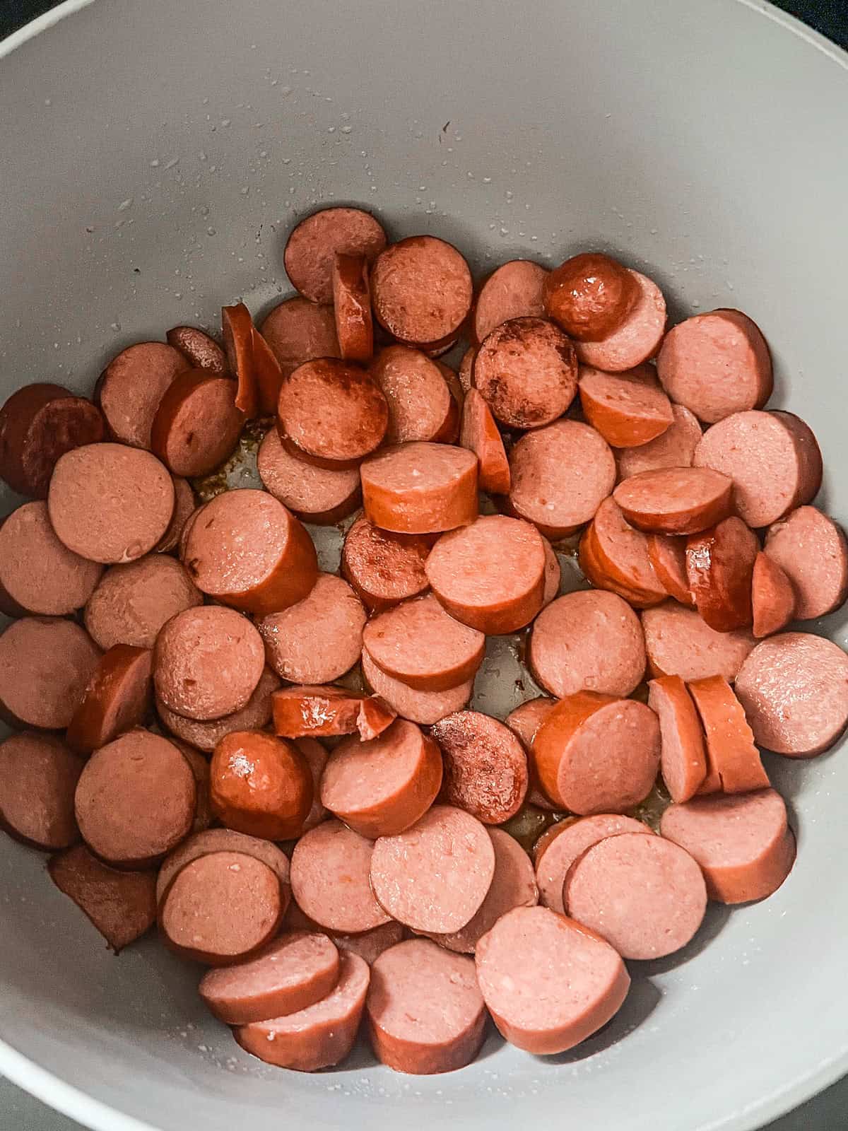 Browning sliced andouille sausage in a dutch oven.