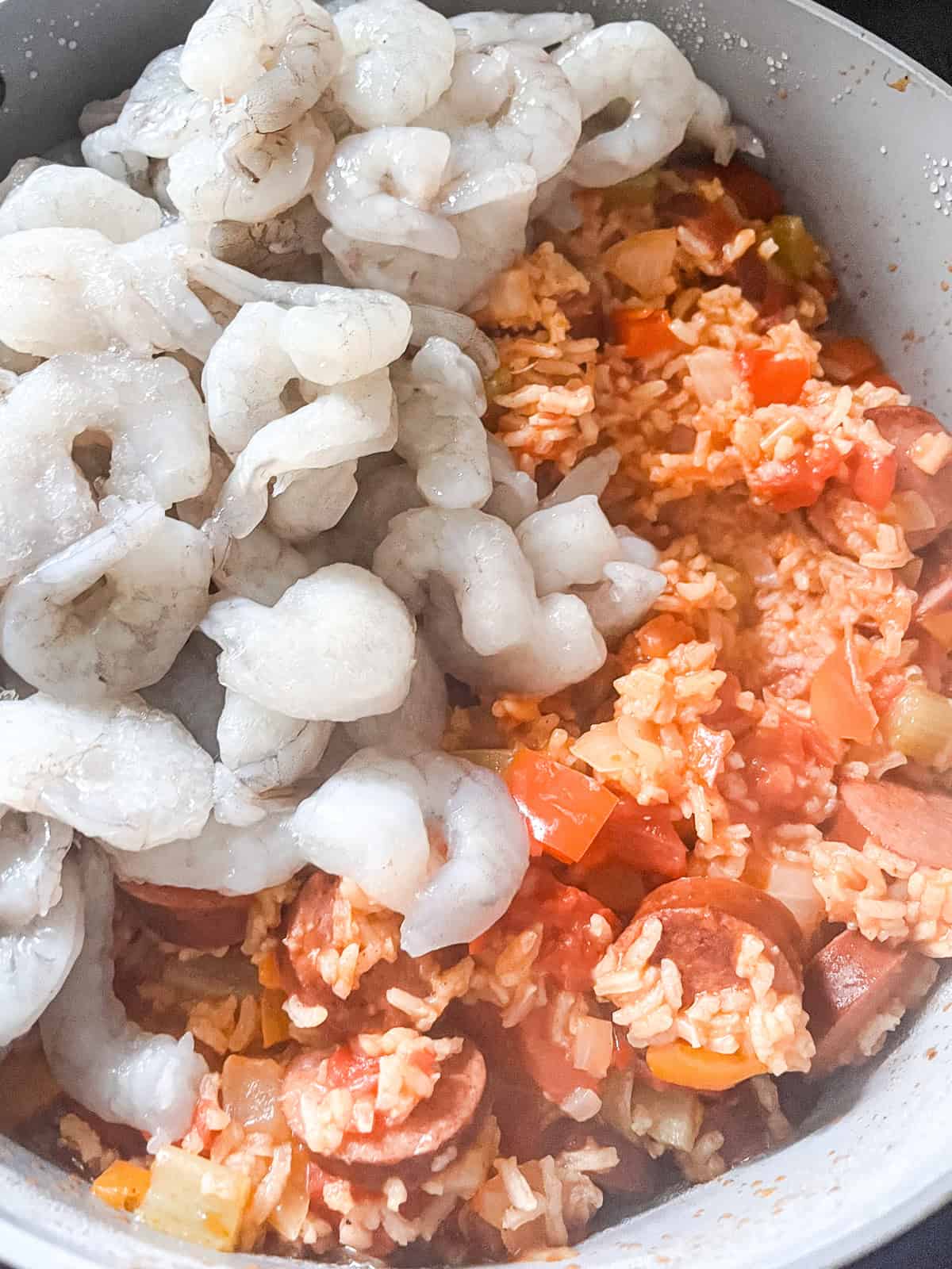 Raw shrimp added to a Dutch oven of jambalaya.
