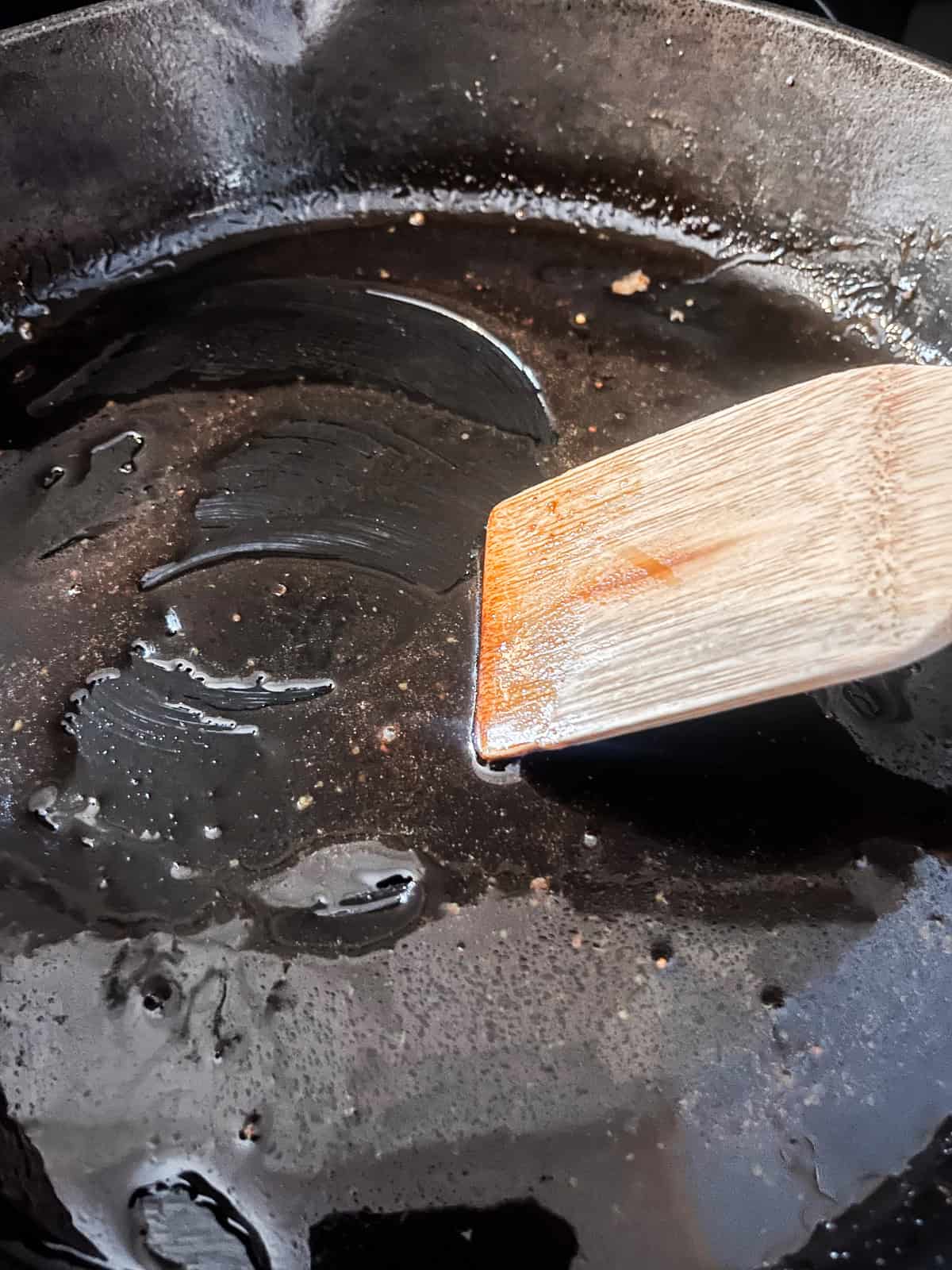 Stirring ham steak glaze in a cast iron skillet.