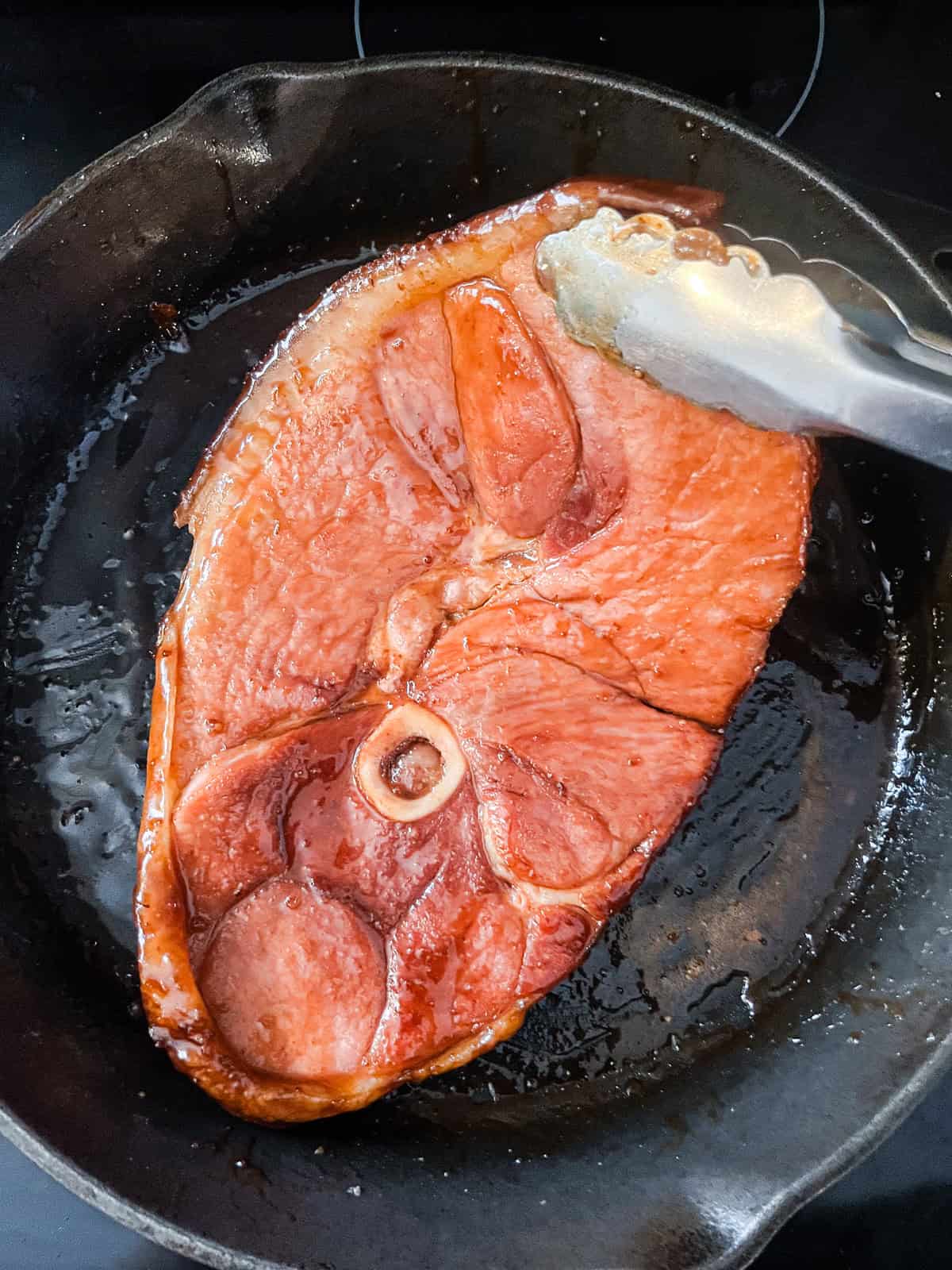 Add a ham steak back into a cast iron skillet with the glaze.