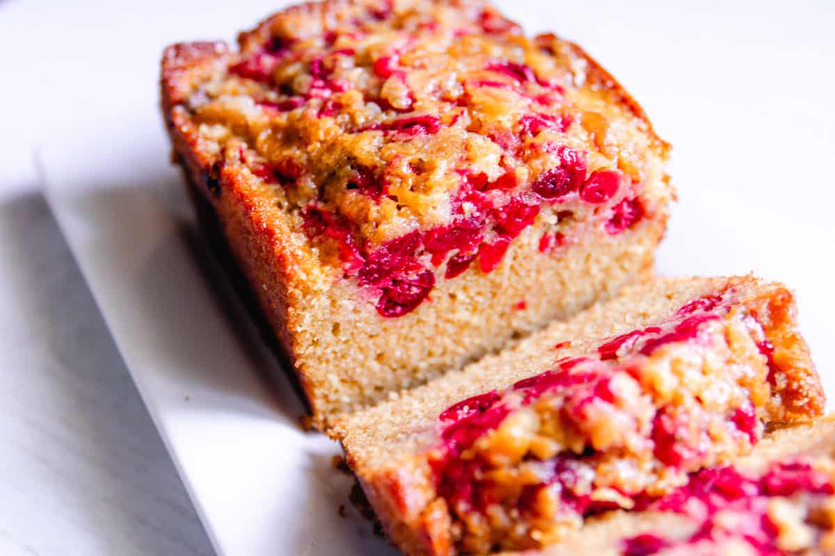 A loaf of freshly milled cranberry bread with a few pieces sliced.
