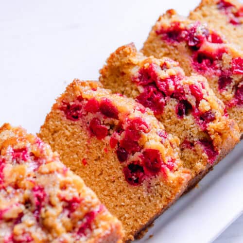Slices of whole grain cranberry bread layered on a white plate.