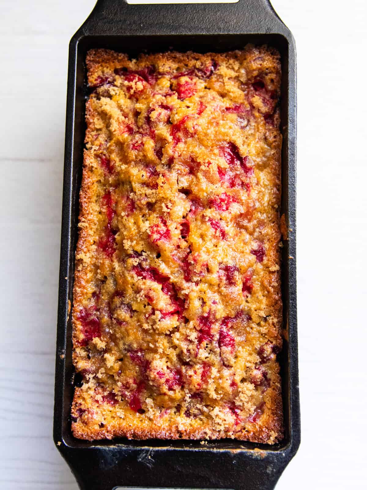 A loaf of freshly milled cranberry bread in a loaf pan, after baking.