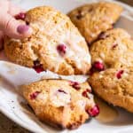 Picking up a scone off of a plate of whole grain cranberry scones.