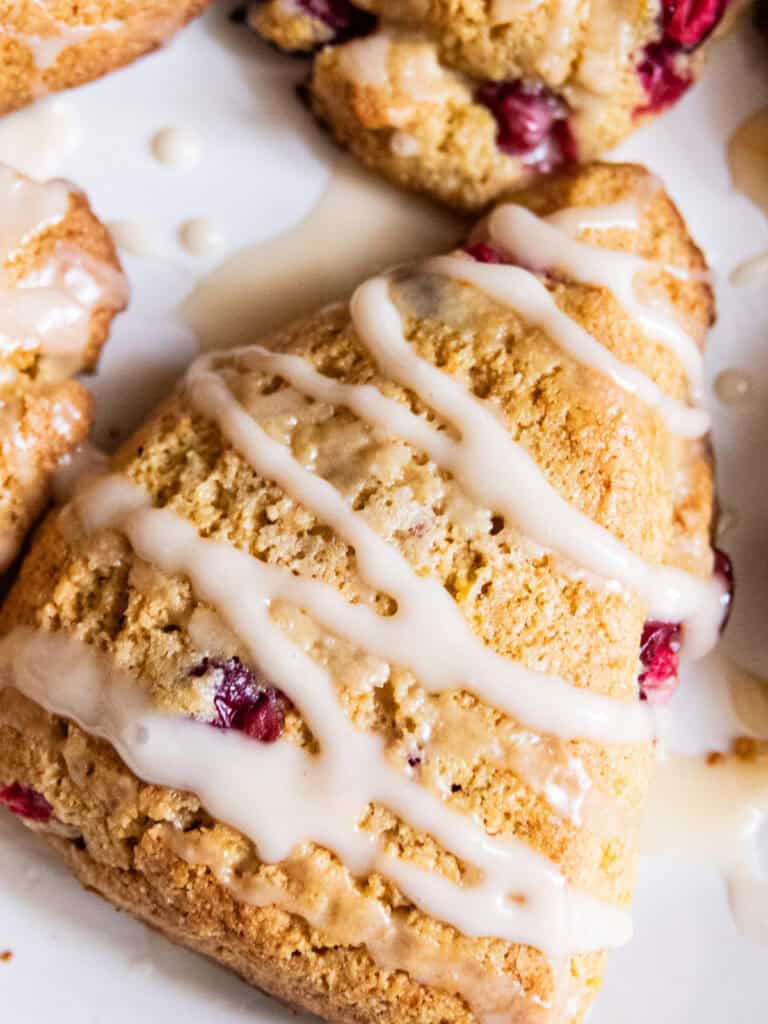 Whole grain cranberry orange scones with glaze on a white plate.