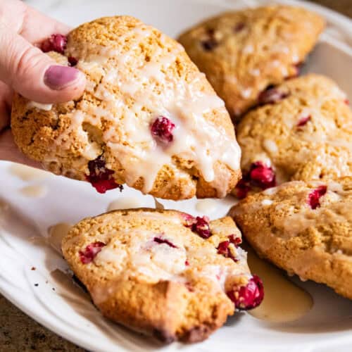 Picking up a scone off of a plate of whole grain cranberry scones.