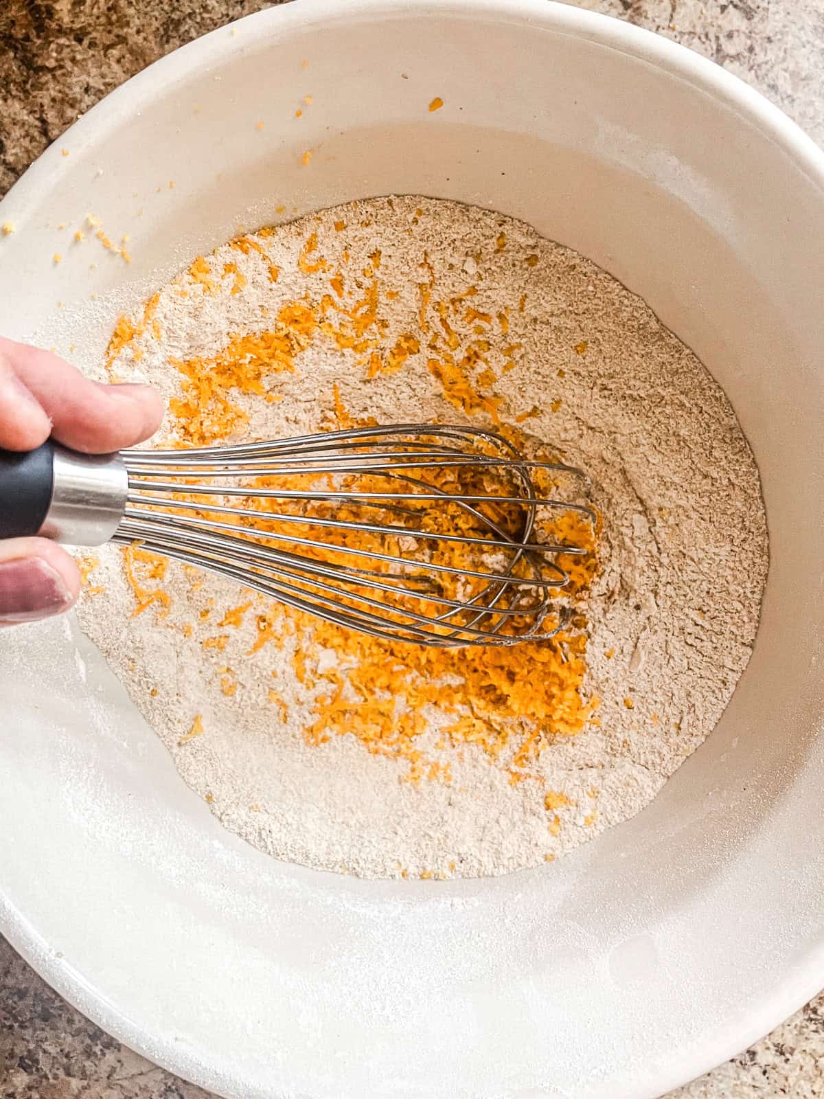 Stirring dry ingredients and orange zest together in a bowl.