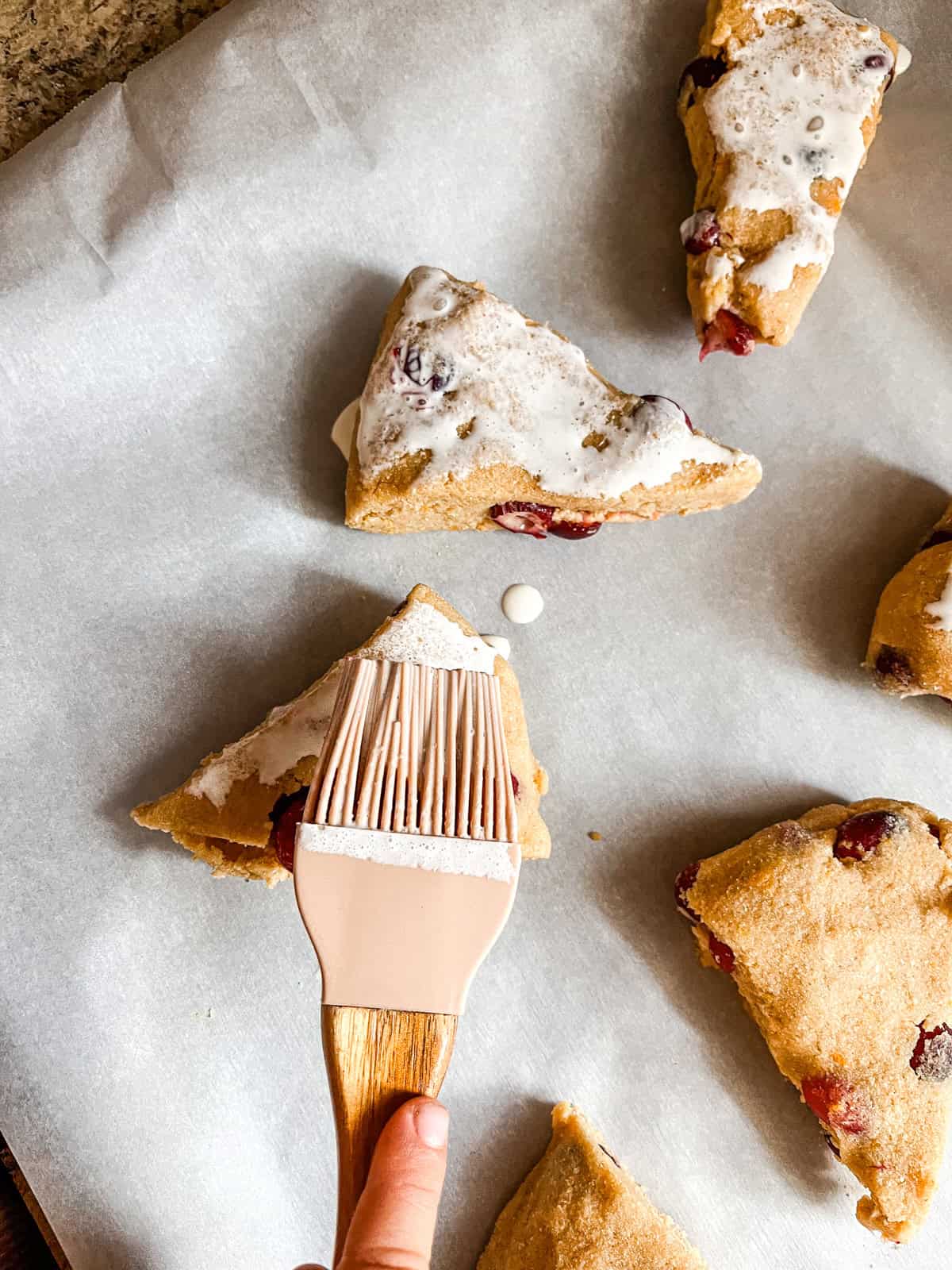 Brushing scones with heavy cream before baking.