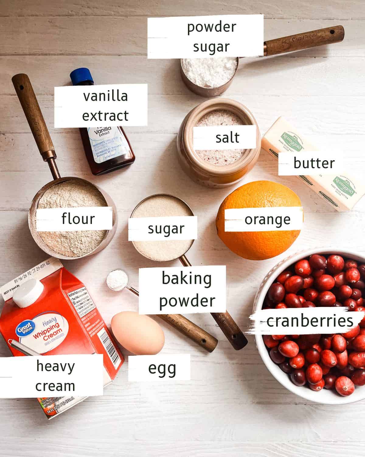 Whole grain cranberry orange scone ingredients labeled on a white table.