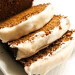 A sliced loaf of whole grain ginger bread with white frosting on top.