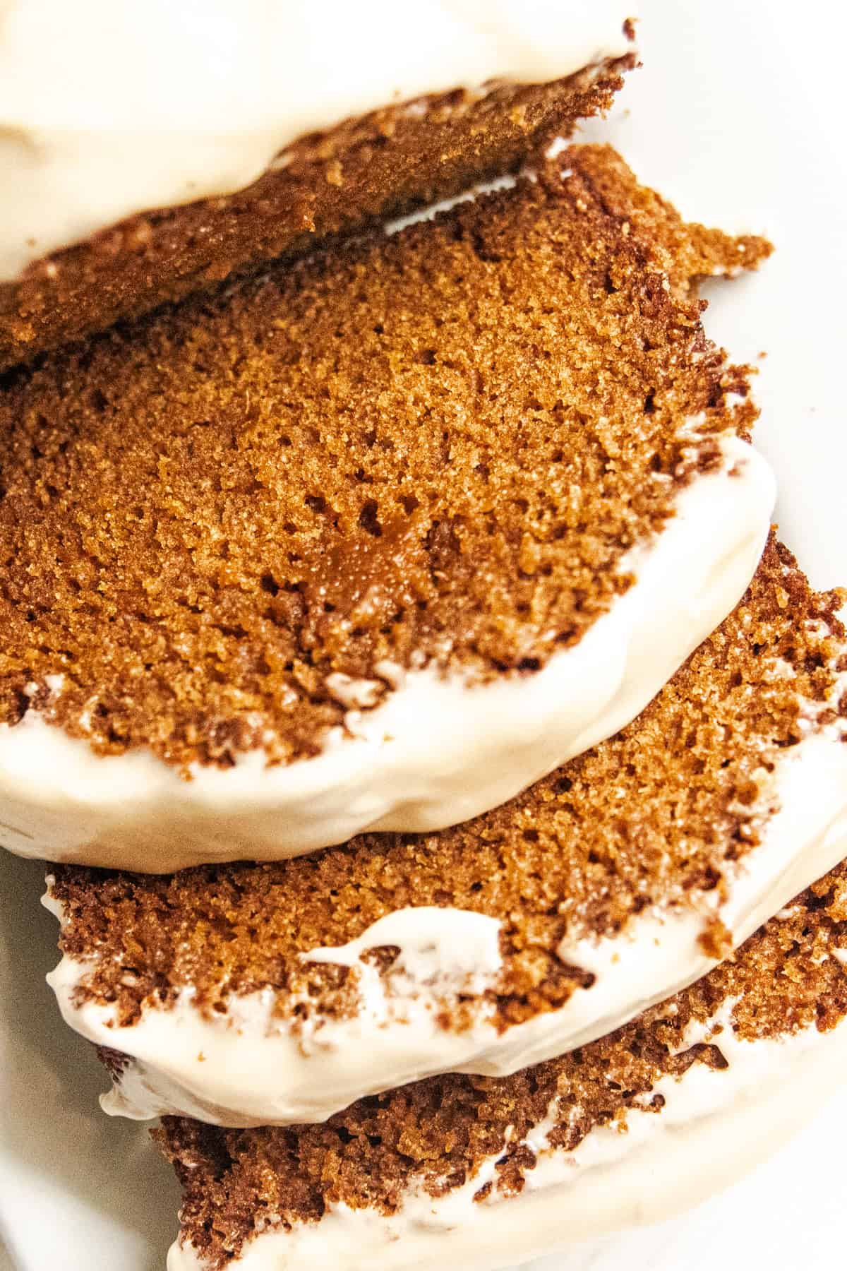 A sliced loaf of ginger bread with frosting on top.