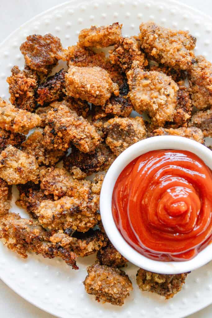 Venison nuggets on a white plate with a bowl of ketchup for dipping.