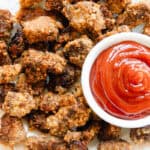 Venison nuggets on a white plate with a bowl of ketchup.