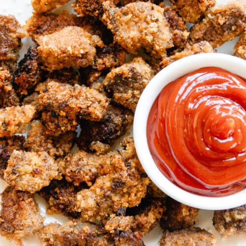 Venison nuggets on a white plate with a bowl of ketchup.