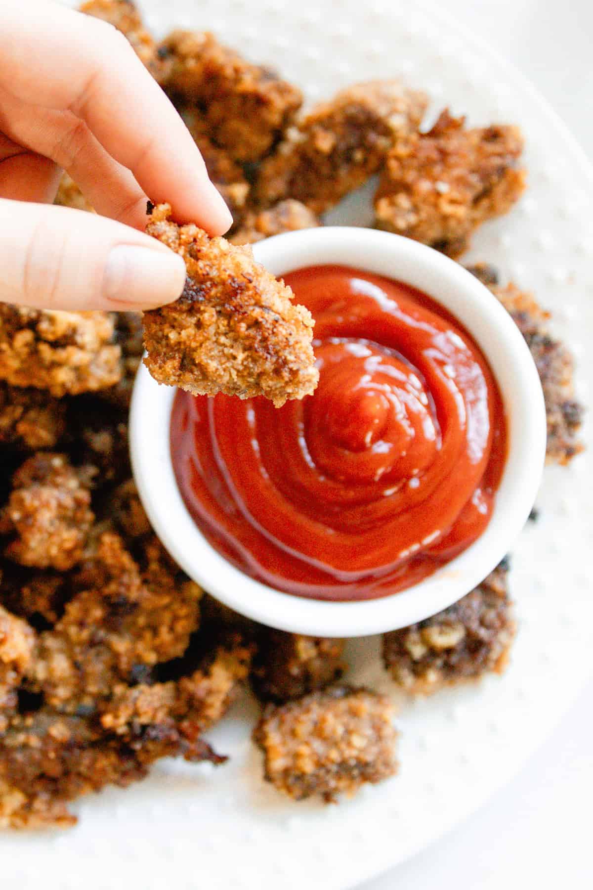 Dipping a venison nugget in a bowl of ketchup.