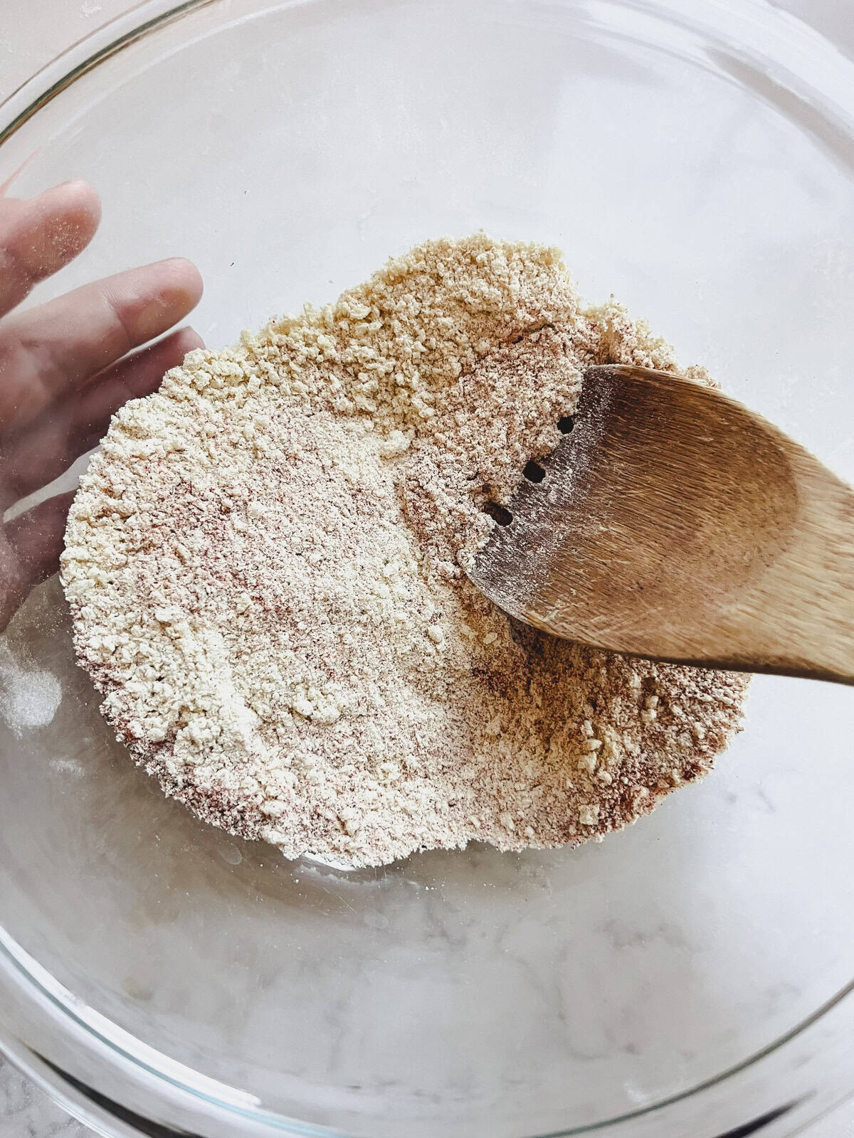 Stirring flour and spices in a glass mixing bowl.