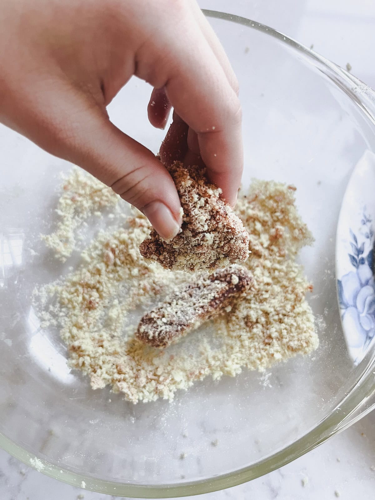 Coating a venison bite in bread crumbs.