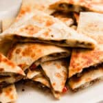 Venison quesadillas cut in triangles on a white plate.