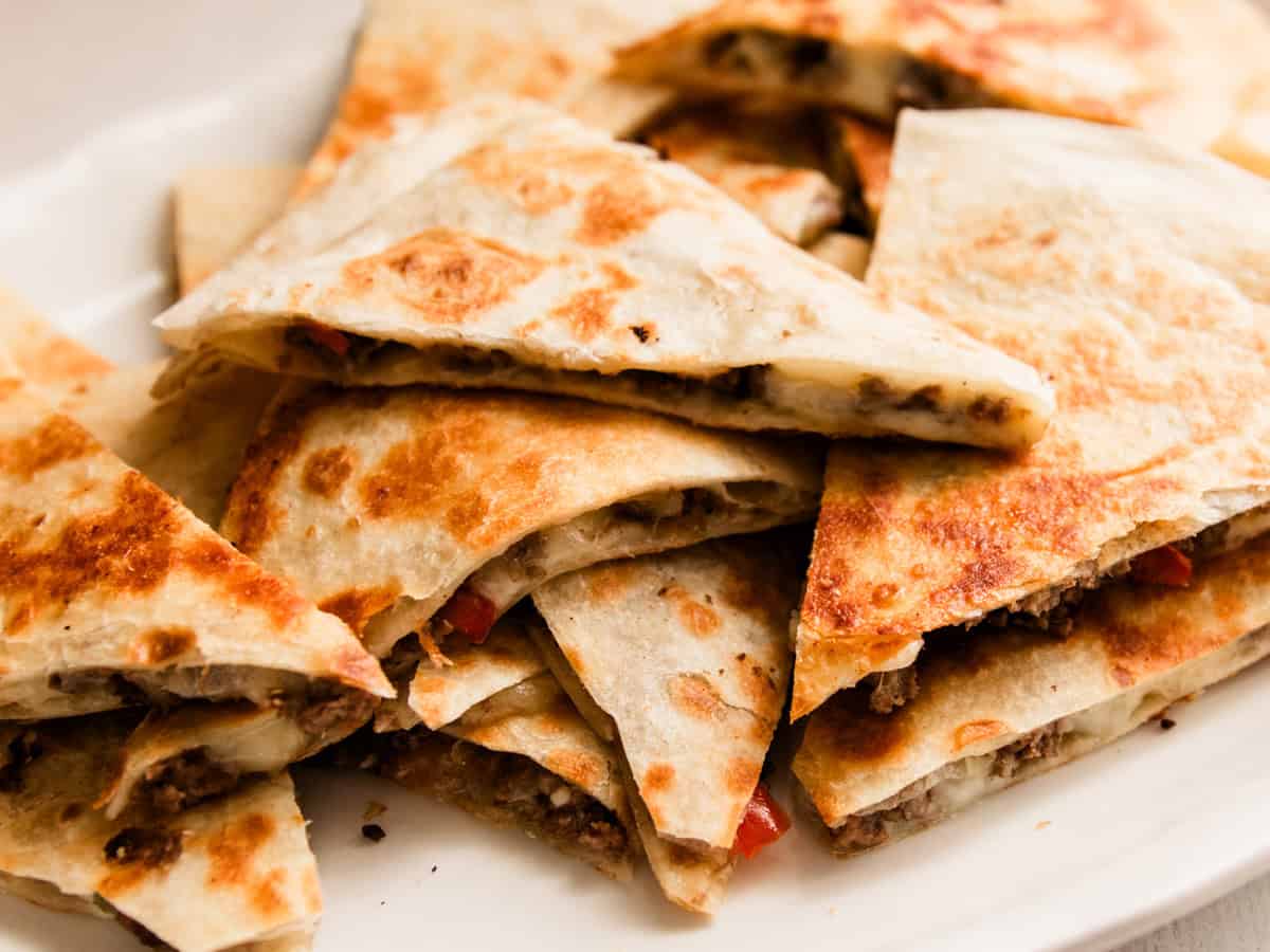 Venison quesadillas cut in triangles on a white plate.
